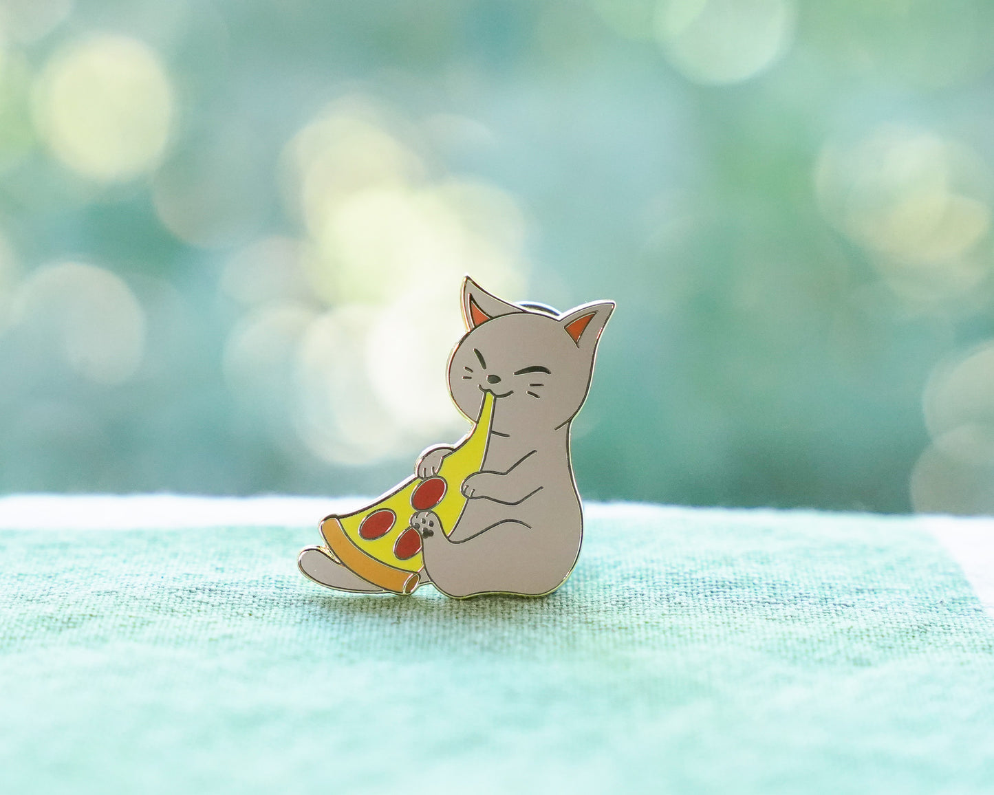 A pin featuring a gray cat happily eating a piece of pizza