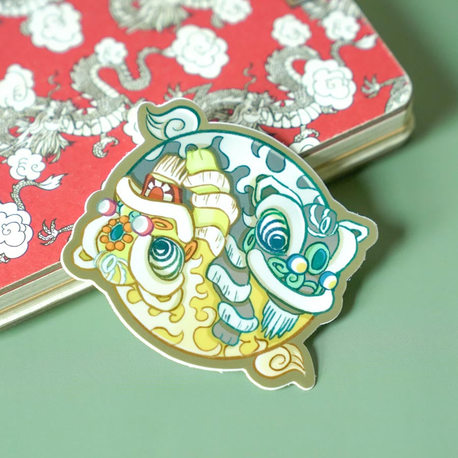 Yin Yang Fut San Hok San Lion Dance Sticker on a light green background by a red notebook