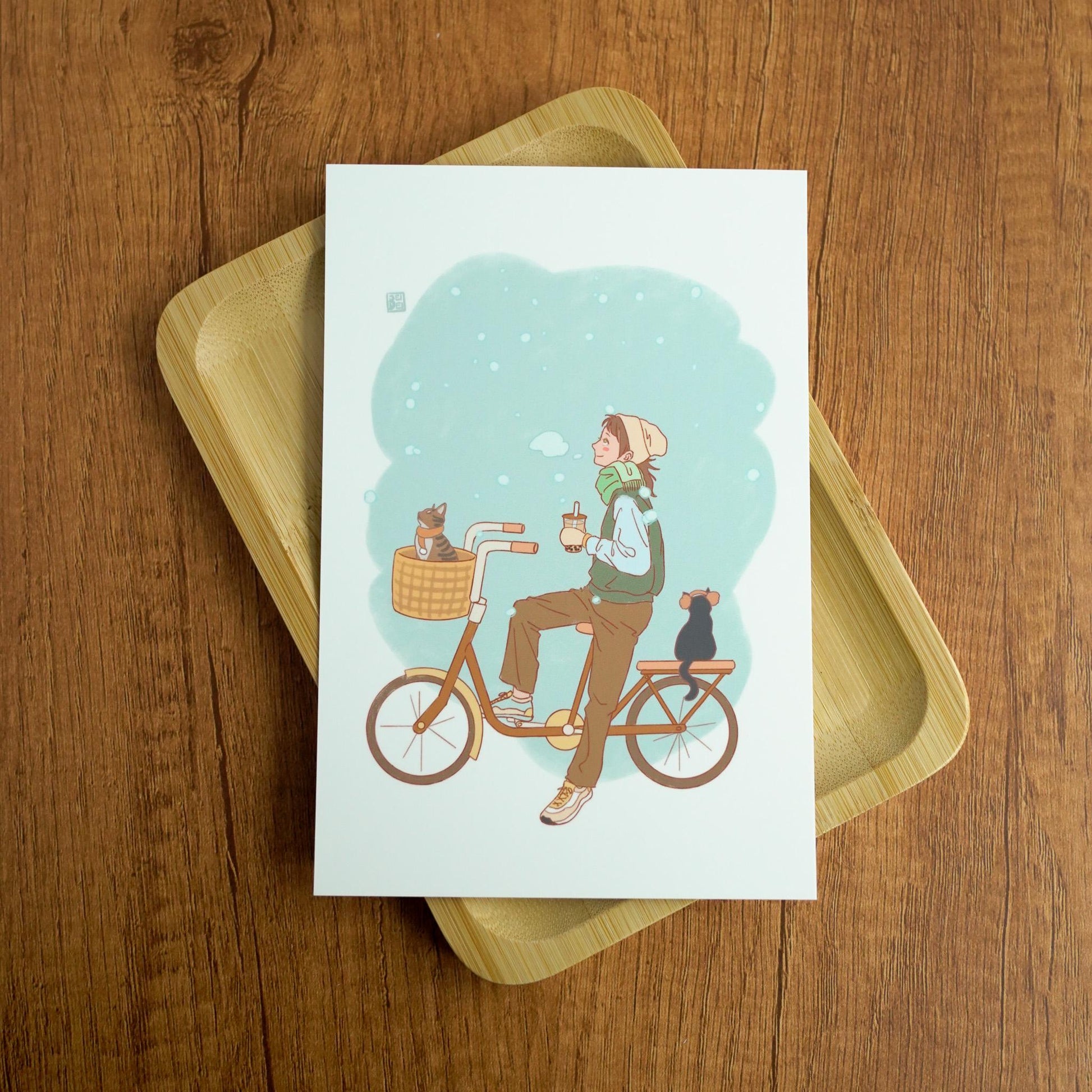 Bicycle Cats Postcard - Girl in sweatshirt riding a bicyle with 2 cats and holding a boba Tea in snowy winter